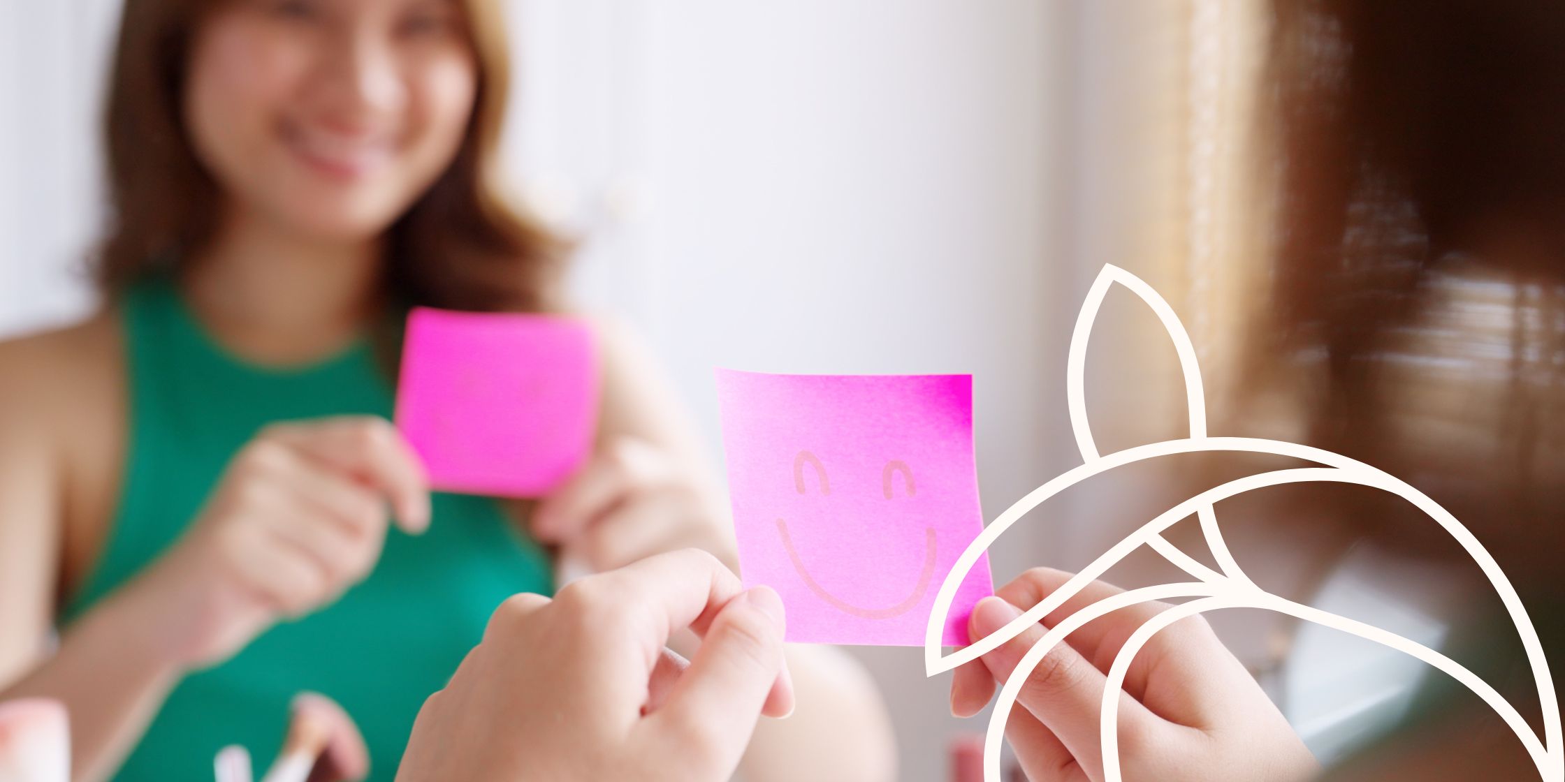 Mom looking into the mirror holding a sticky note with a smiley face drawn on it.