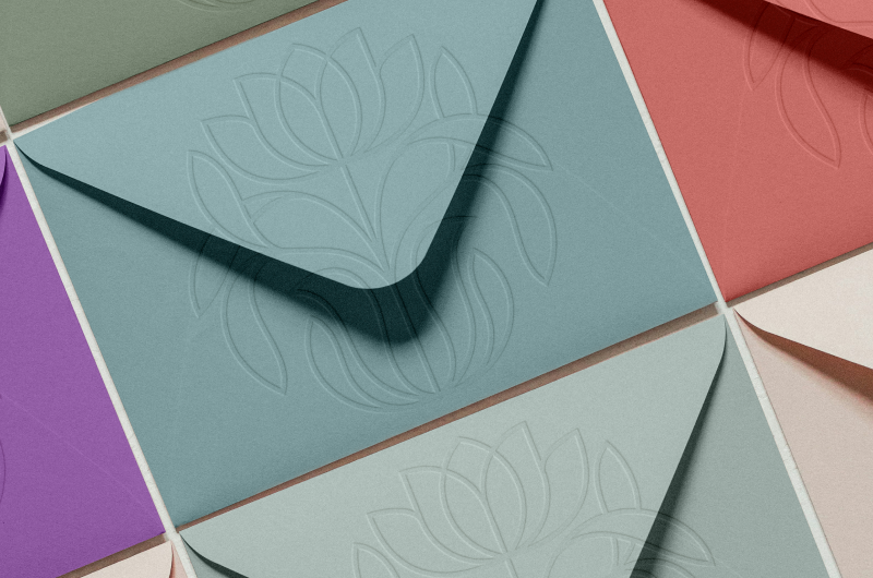 sage green, teal, salmon colored envelopes with nourish nurture thrive logo embossed